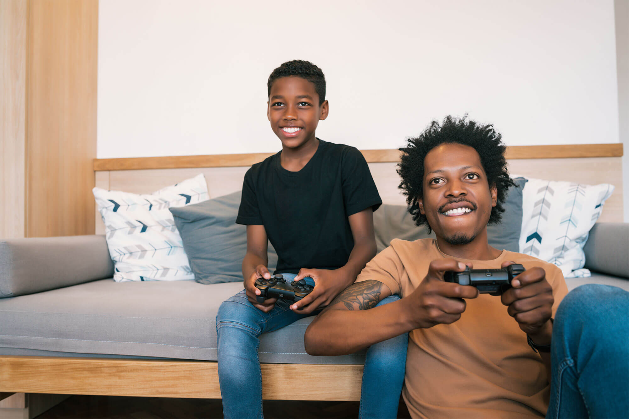 Father sitting on floor and son sitting on couch playing video game