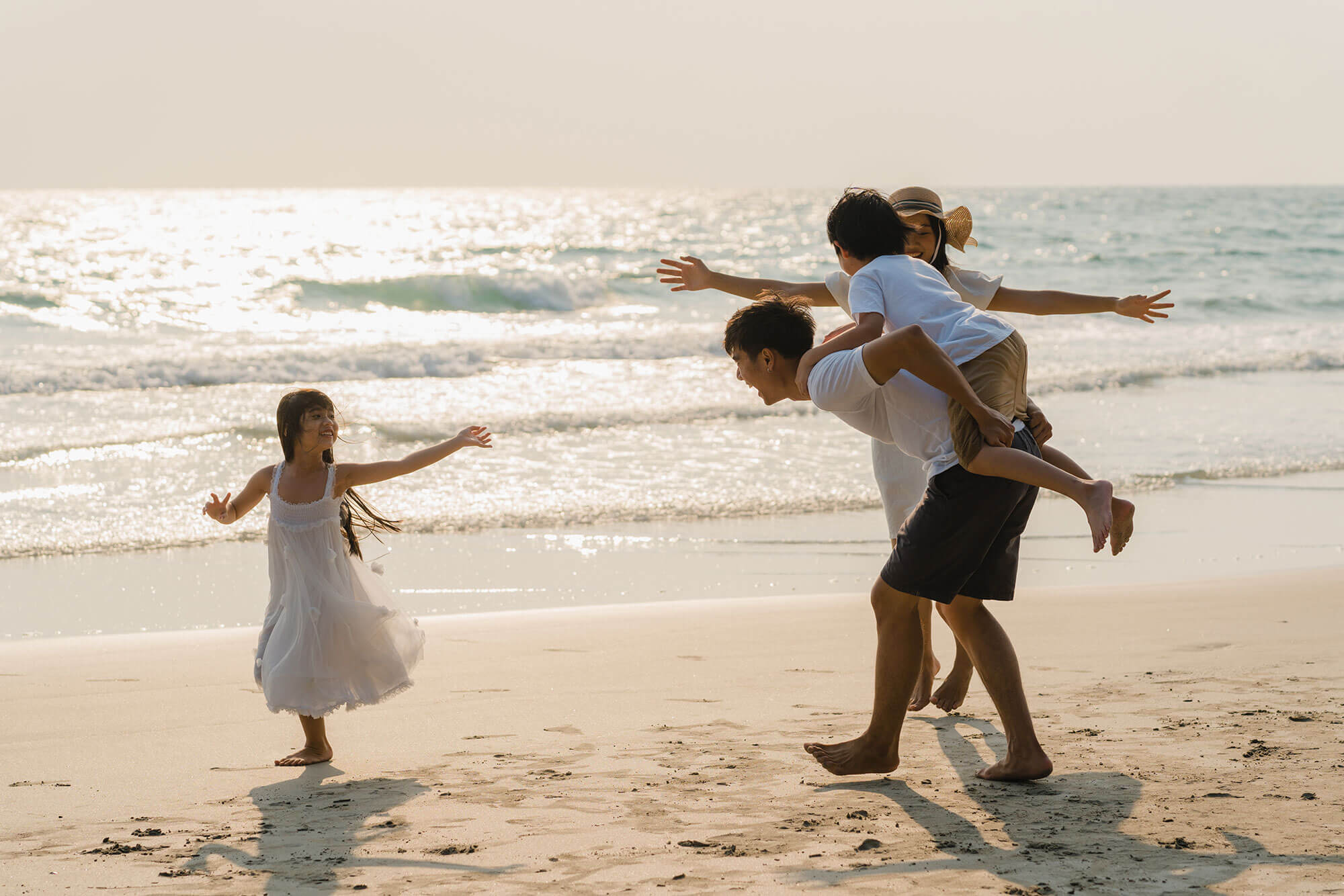 Father and mother playing with children on beach