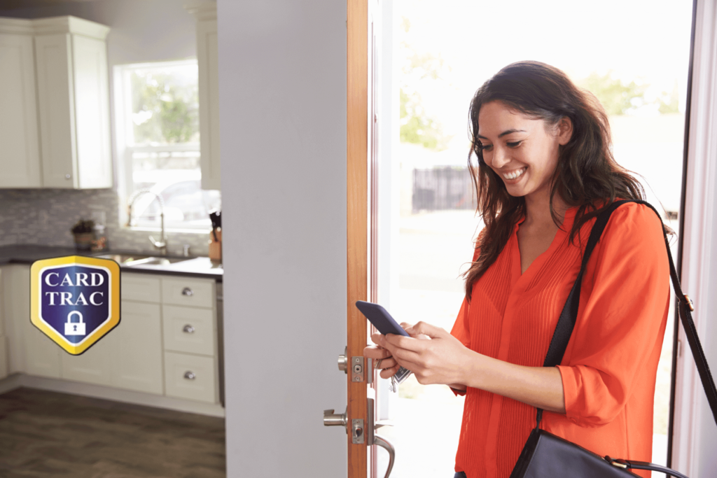 Woman checking phone while walking into home with briefcase on her shoulder and kitchen in background