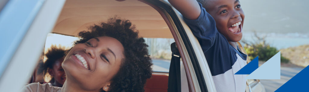 Woman and child in car smiling while child sticks arms and head outside window