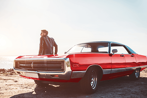 Man standing next to red convertible