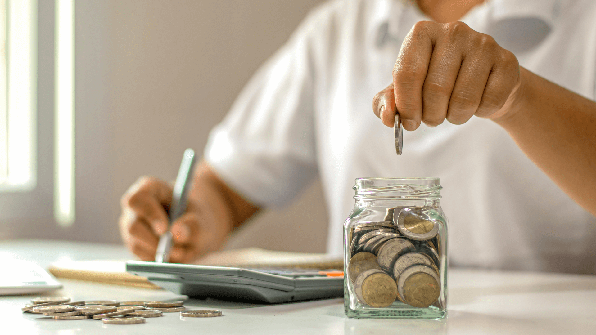 man placing coins in a jar